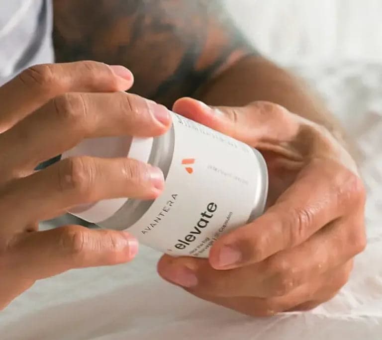 Person holding Avantera Elevate supplement jar, demonstrating daily use